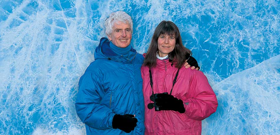 Portrait of Pat and Rosemarie Keough in winter clothing in front of a wall of solid blue ice marbled with white fissures